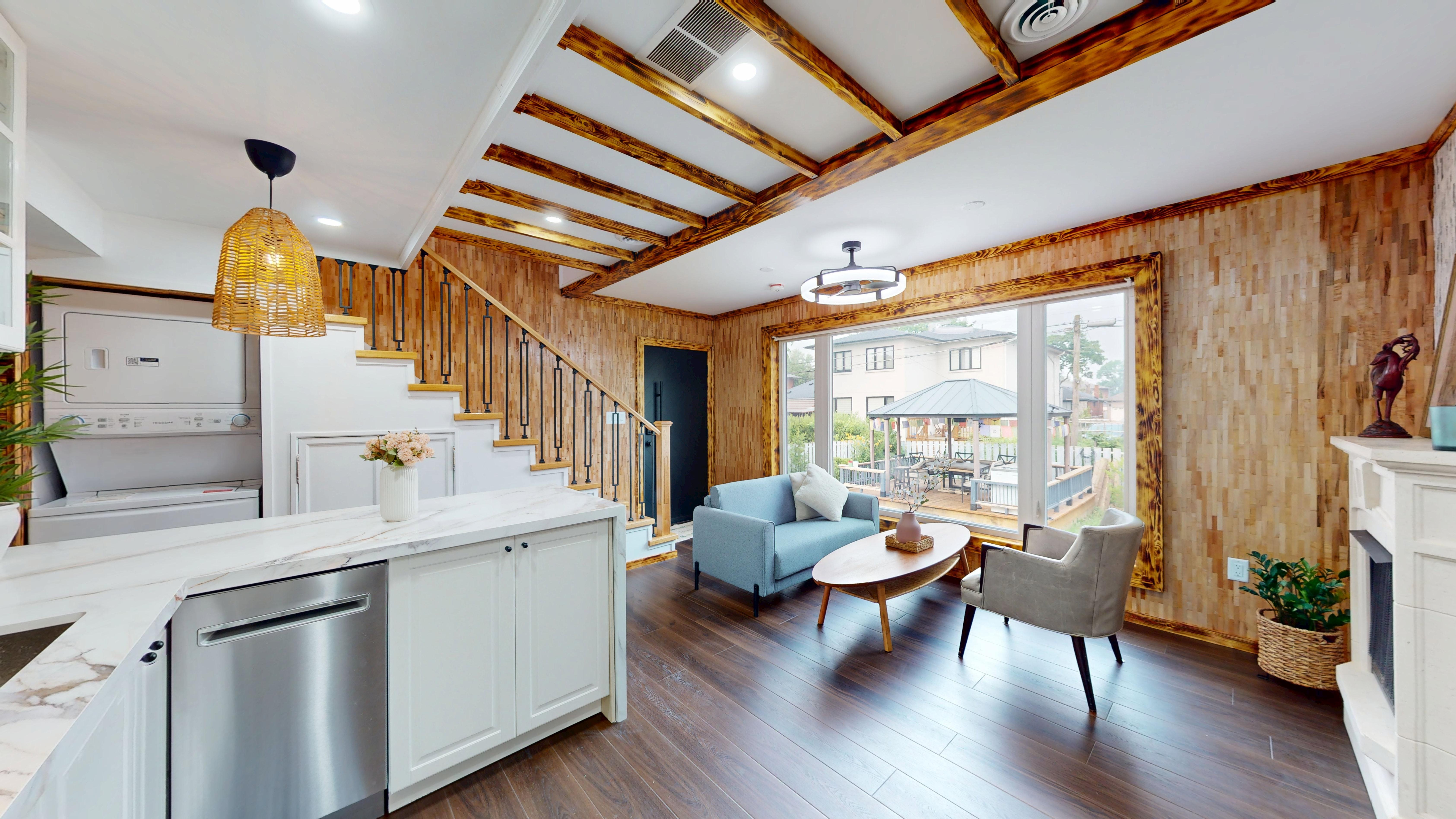 Kitchen and living room from a second angle, showing the staircase and brick backsplash