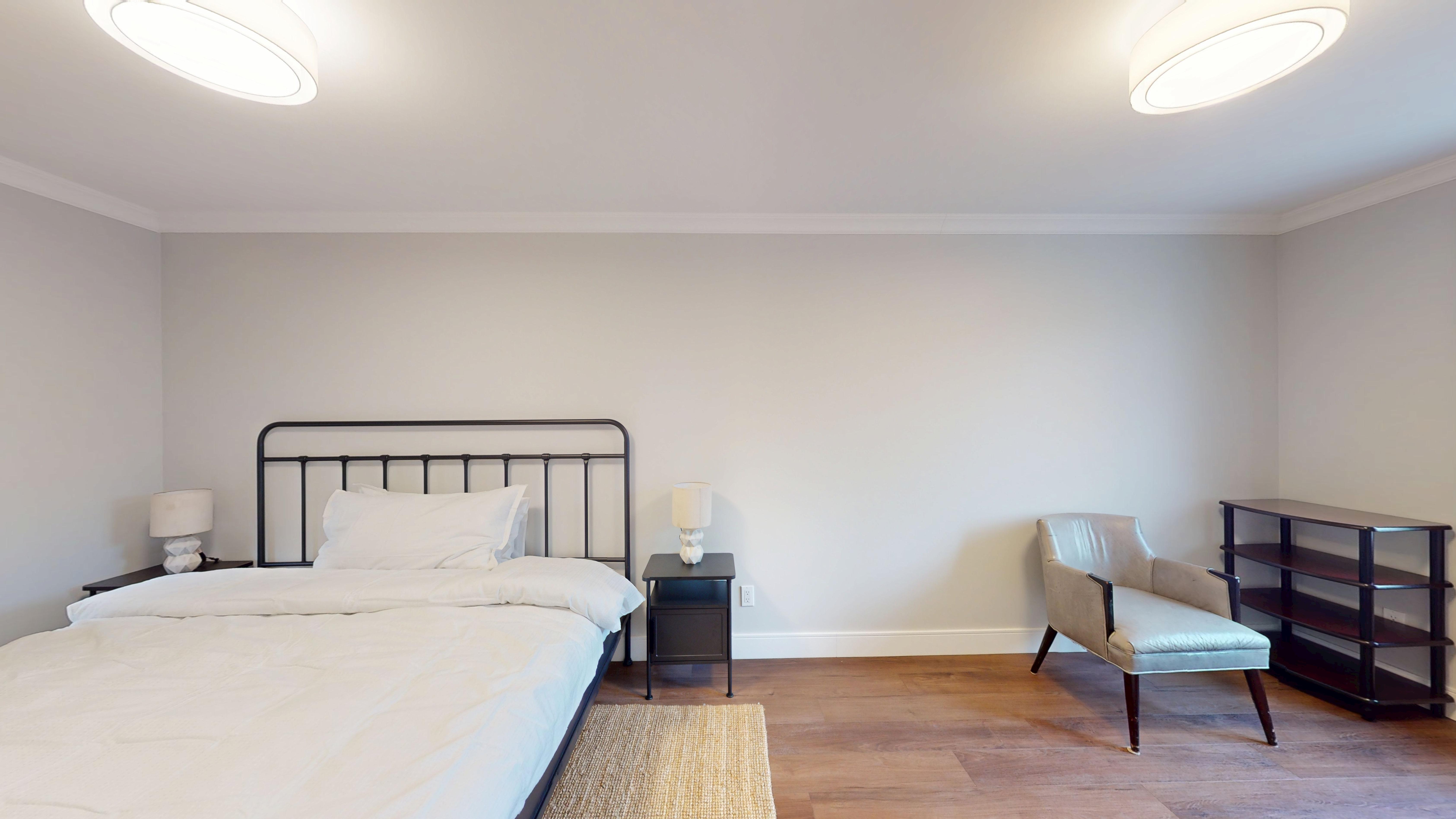 Bedroom 4: the primary suite, with a king bed, armchair and dark wood console