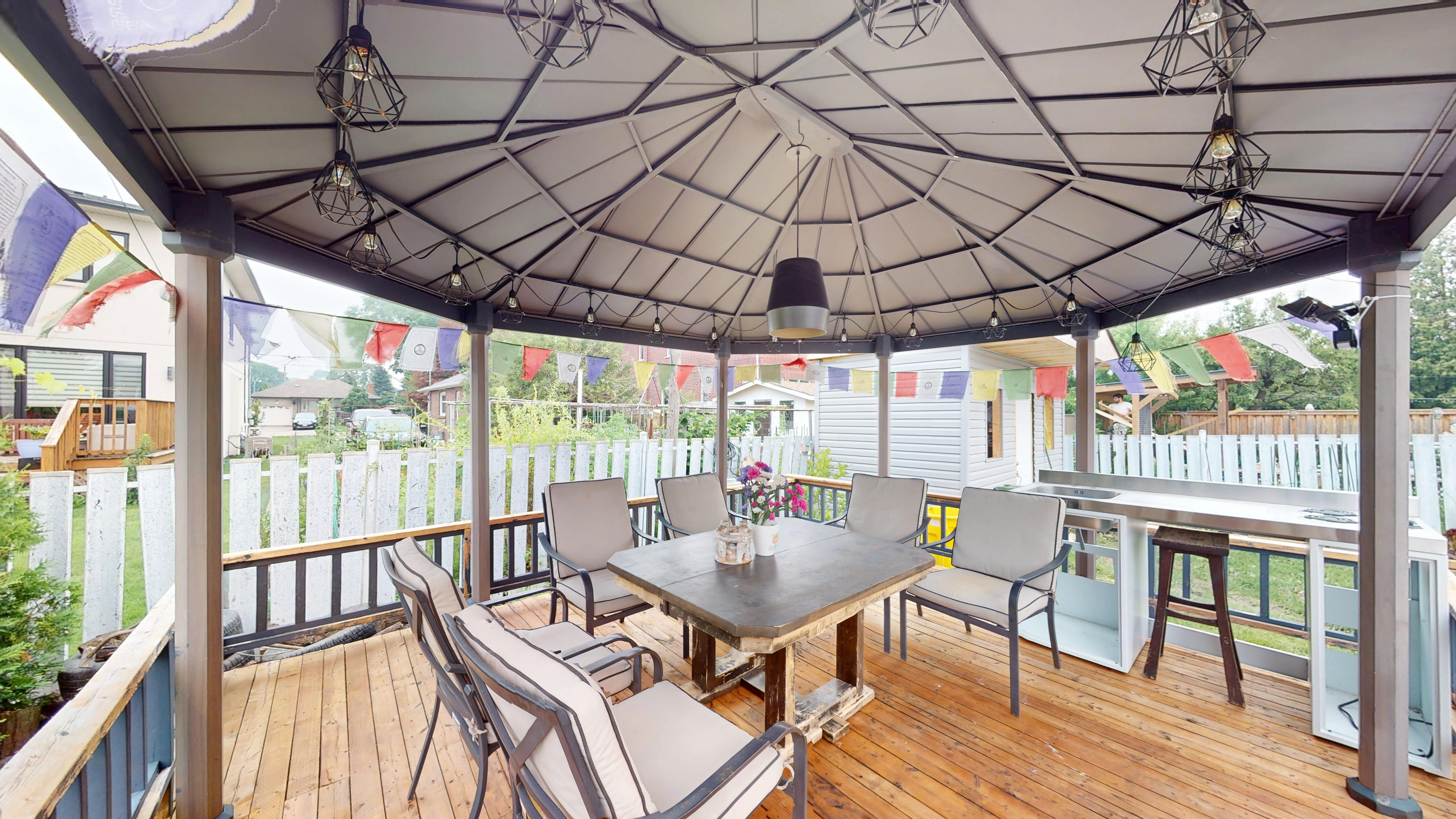 Covered back deck with prayer flags, an outdoor dining table and a small outdoor kitchen